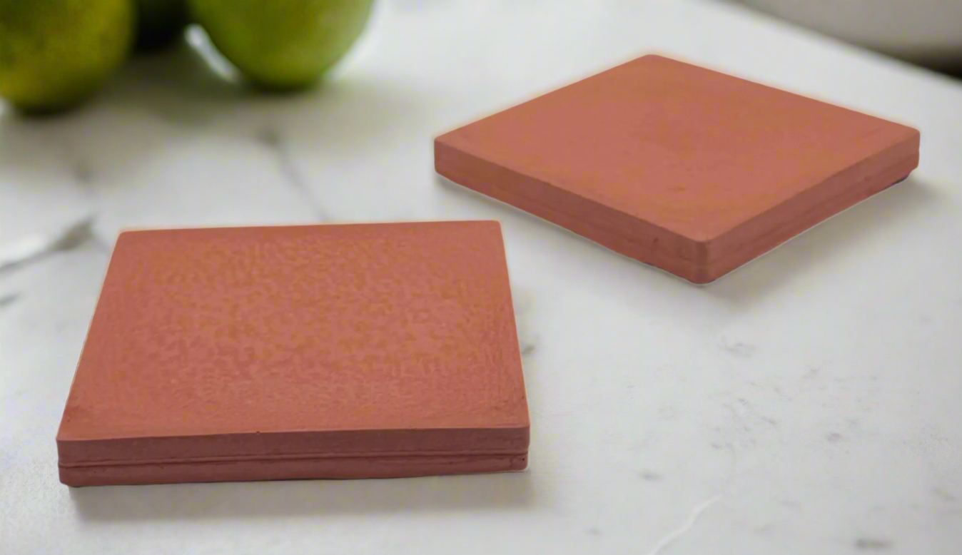 Pair of Coral square concrete coasters with modern rustic finish. Handcrafted item on white background.