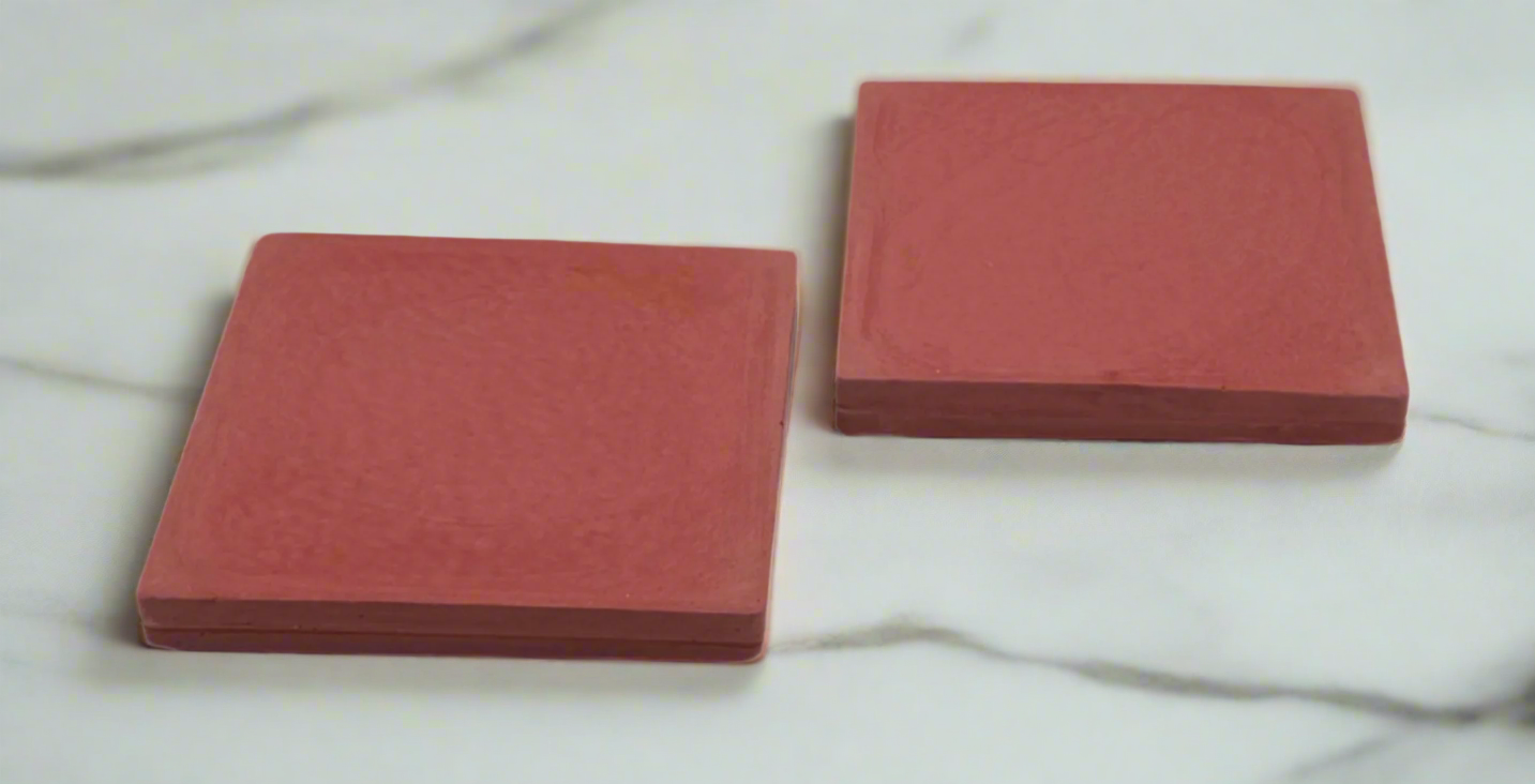 Two barn red square concrete coasters on white background. Handcrafted modern rustic design.