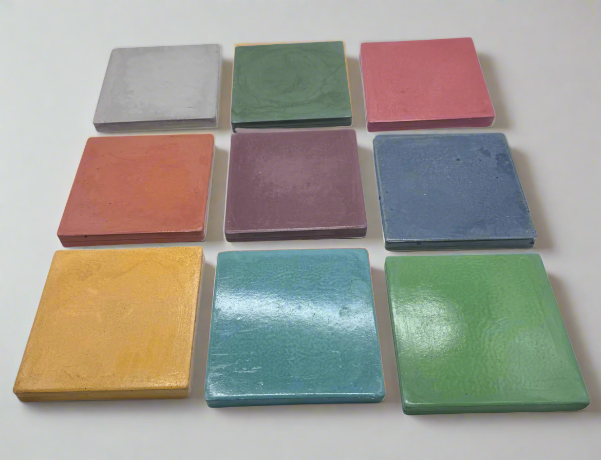 ine glossy square concrete coasters in Cement Grey, Green, Barn Red, Coral, Mauve, Dark Blue, Honey Yellow, Turquoise, and Dark Green, arranged in a three-by-three grid on a white background.