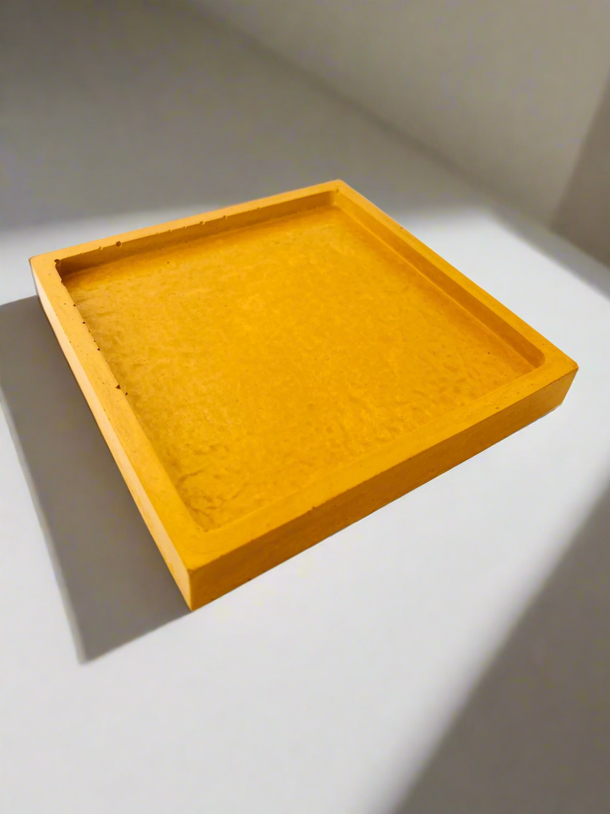 A single glossy Honey Yellow square concrete coaster tray is angled slightly on a white background, showcasing its subtle lip.