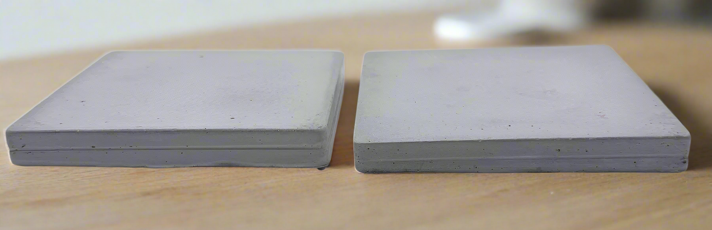Pair of handcrafted square concrete coasters in ivory white. Side view displays substantial thickness.