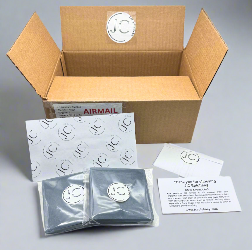 JC Epiphany packaging set: Box has Air Mail tag, insert, 2 dark blue coasters in clear branded wrap.