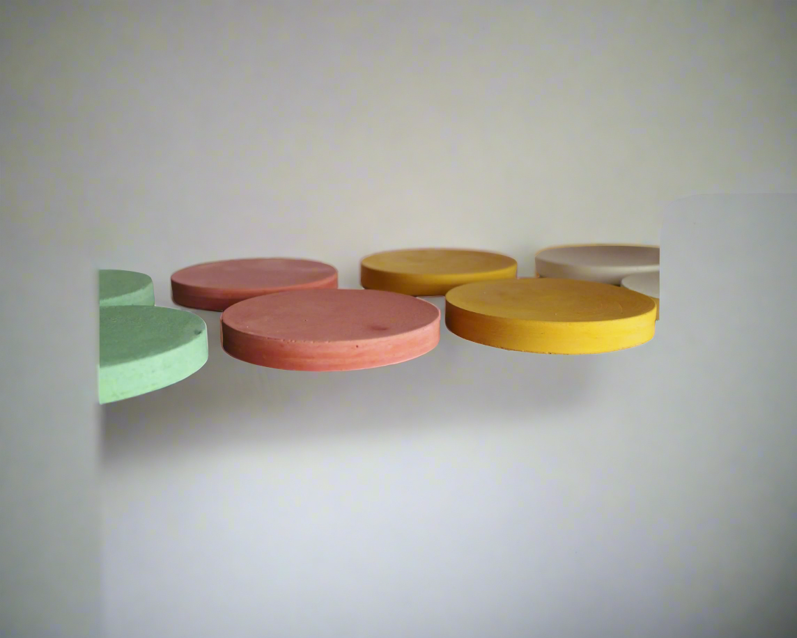 Three round handmade concrete drink coasters are partially visible in a row against a white background: one in Barn Red, one in Green, and one in Ivory White, showcasing the earthy tones and circular design of this modern rustic set.
